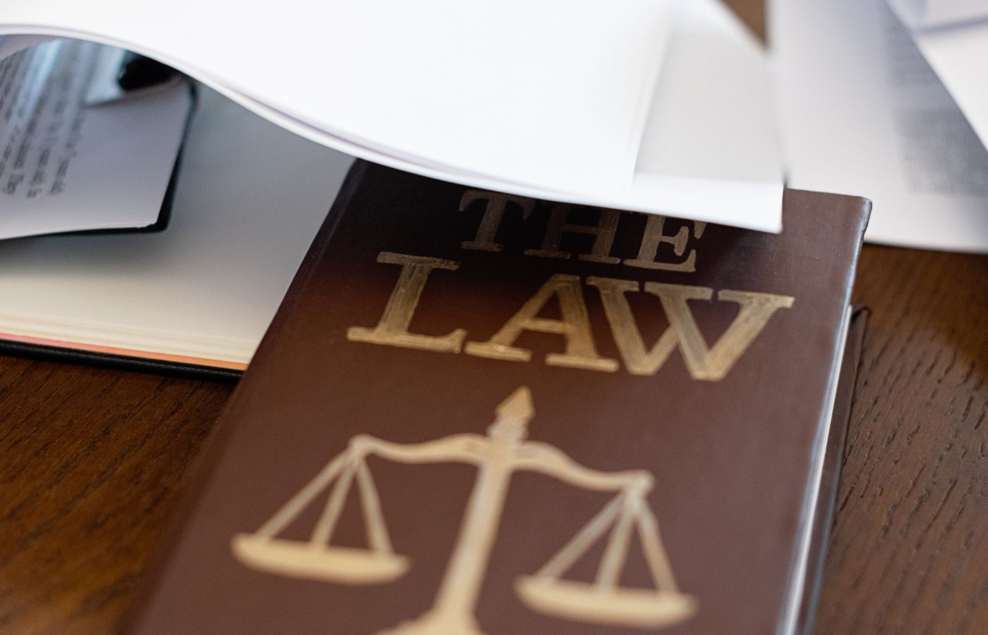 Juridisch wetboek met dossierstukken op een houten bureau